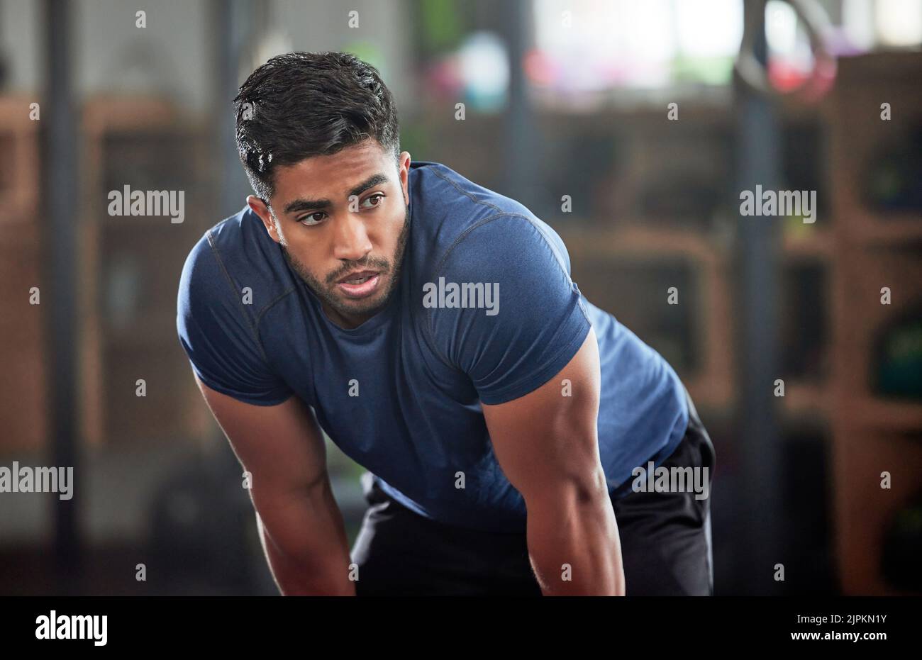 Tired, breathing and fitness gym man taking a break from workout, training or exercising inside a wellness center. Young athletic, masculine guy Stock Photo