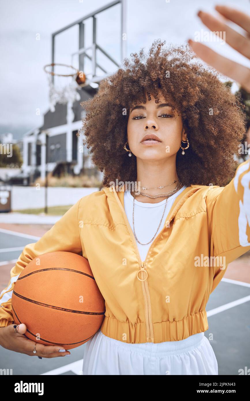 Female basketball player taking selfie on court, looking confident and