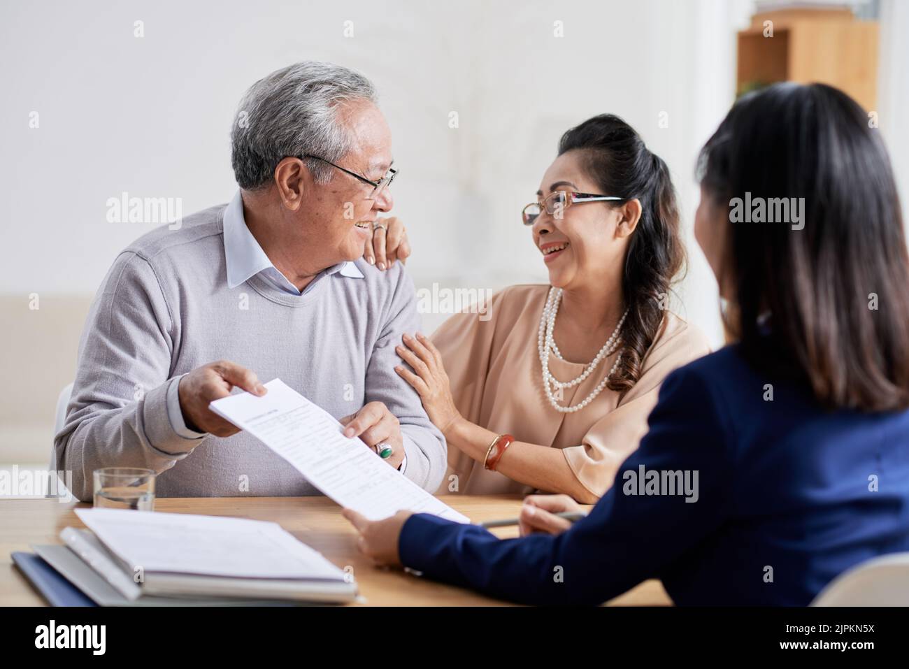 Happy senior Vietnamese couple in office of financial analyst Stock