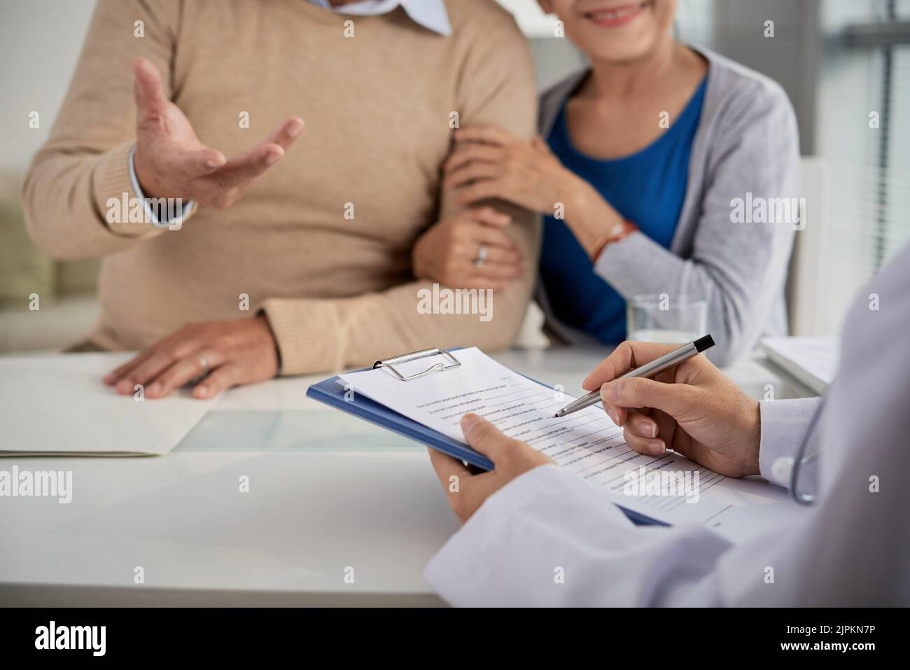 Doctor taking notes when talking to senior couple Stock Photo