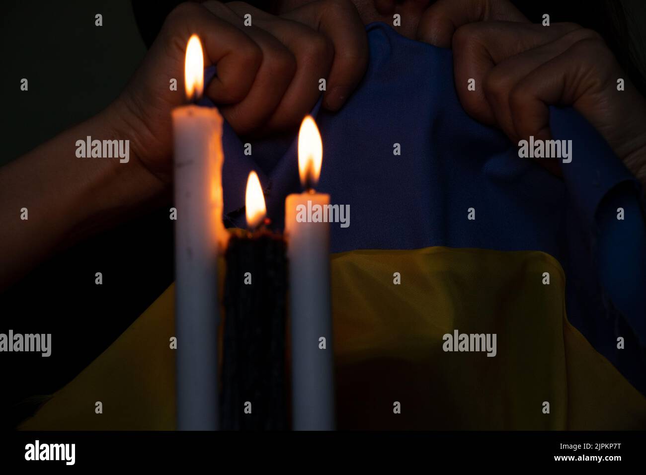 The girl holds in her hands the national flag of Ukraine, a candle, a