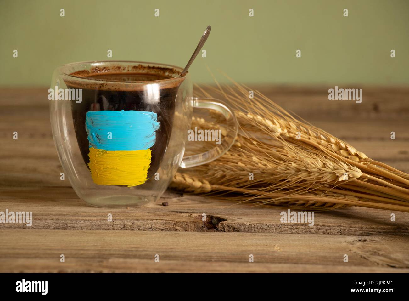 The yellow-blue flag of Ukraine is painted on a white cup with coffee on the table near the wheat field in Ukraine, stop the war Stock Photo