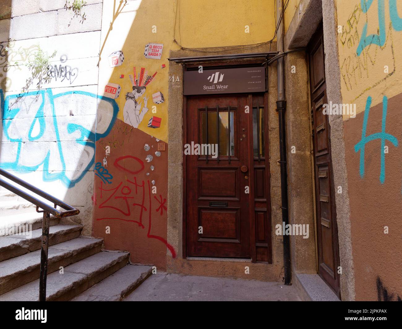 Graffiti and wall art beside a brown door in Porto, Portugal. Stock Photo