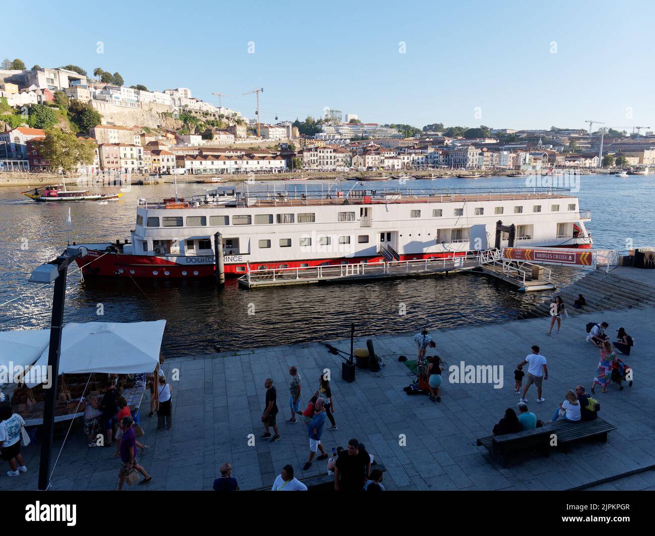 Boat in the River Douro docked at a jetty on in the Riberia district of Porto, Portugal. Vila Nova de Gaia is in the background. Stock Photo