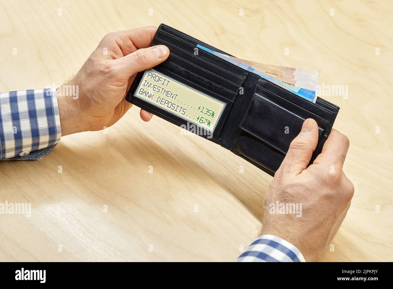 Man hands hold wallet with electronic screen showing investment profit percent and money inside at table. Employment and profit concept closeup Stock Photo