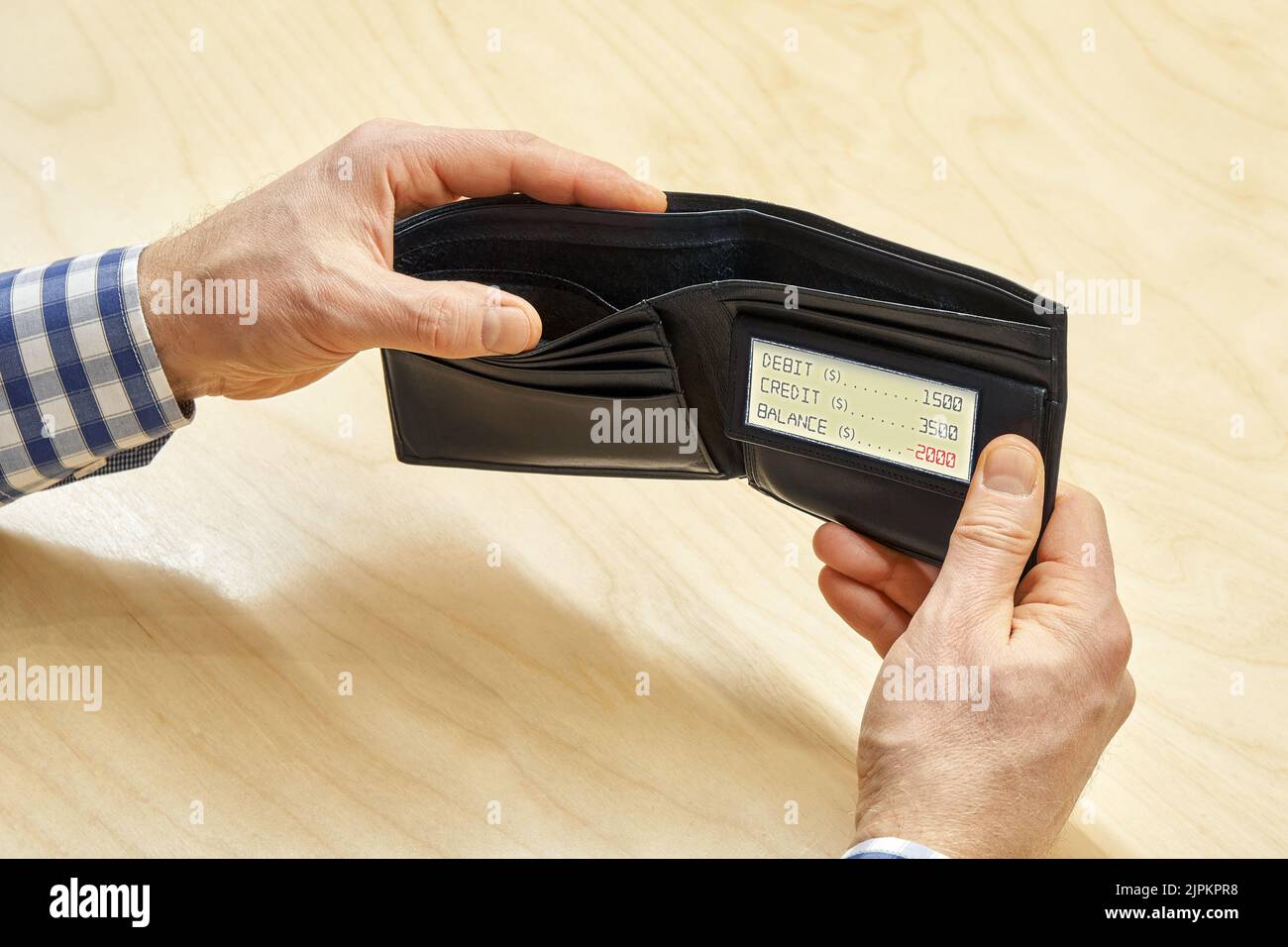 Man hands hold empty black wallet with electronic screen displaying negative balance at table. Poverty and crisis concept closeup Stock Photo