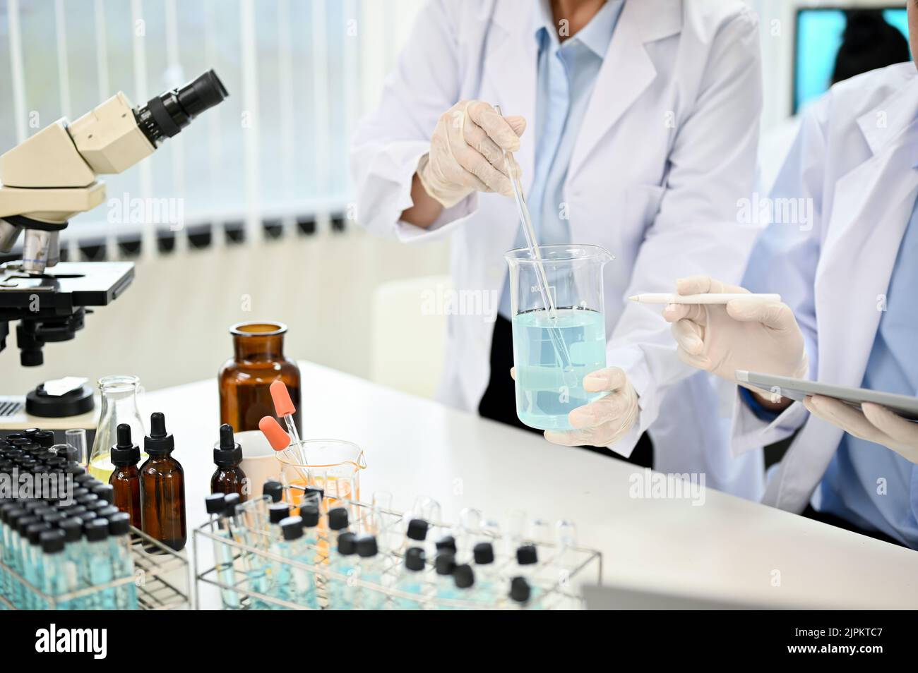 Two expert female scientist in white gown working and testing a new chemical sample together in the laboratory. cropped and close-up image Stock Photo