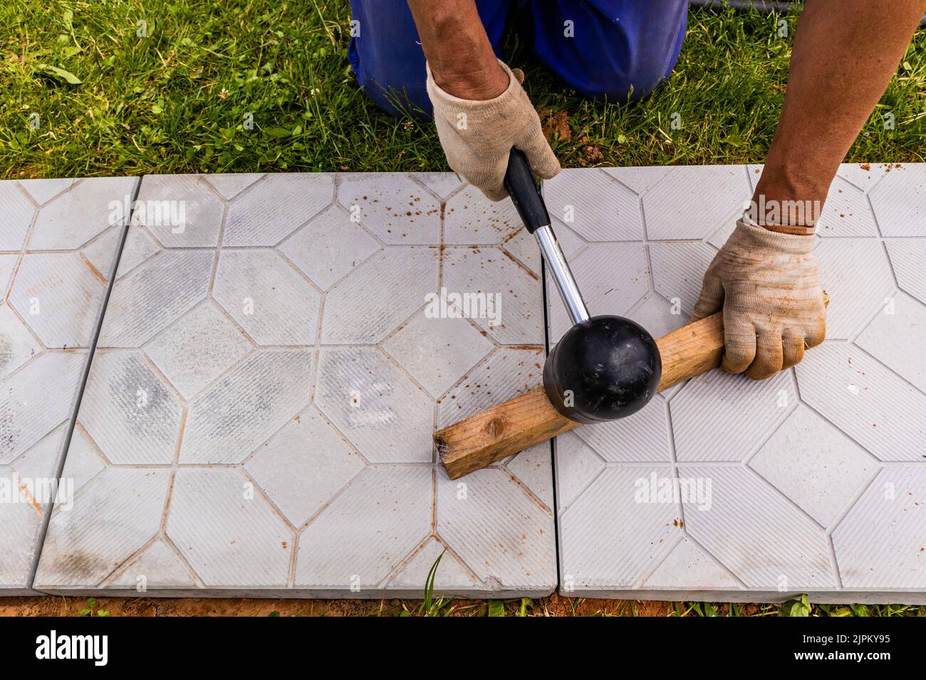 The master lays paving stones in layers. Garden brick pathway paving