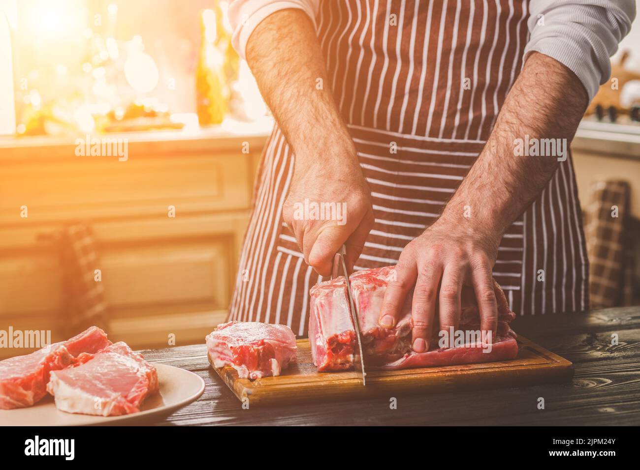 https://c8.alamy.com/comp/2JPM24Y/man-cuts-of-fresh-piece-of-beef-on-a-wooden-cutting-board-in-the-home-kitchen-2JPM24Y.jpg