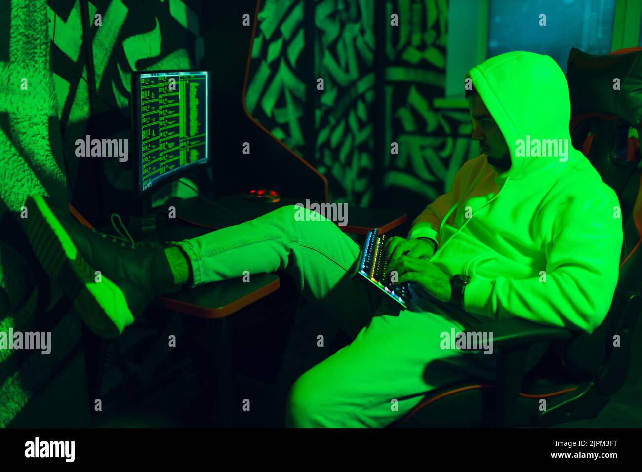 Hacker in hoodie working hacks code site on personal computer Stock Photo