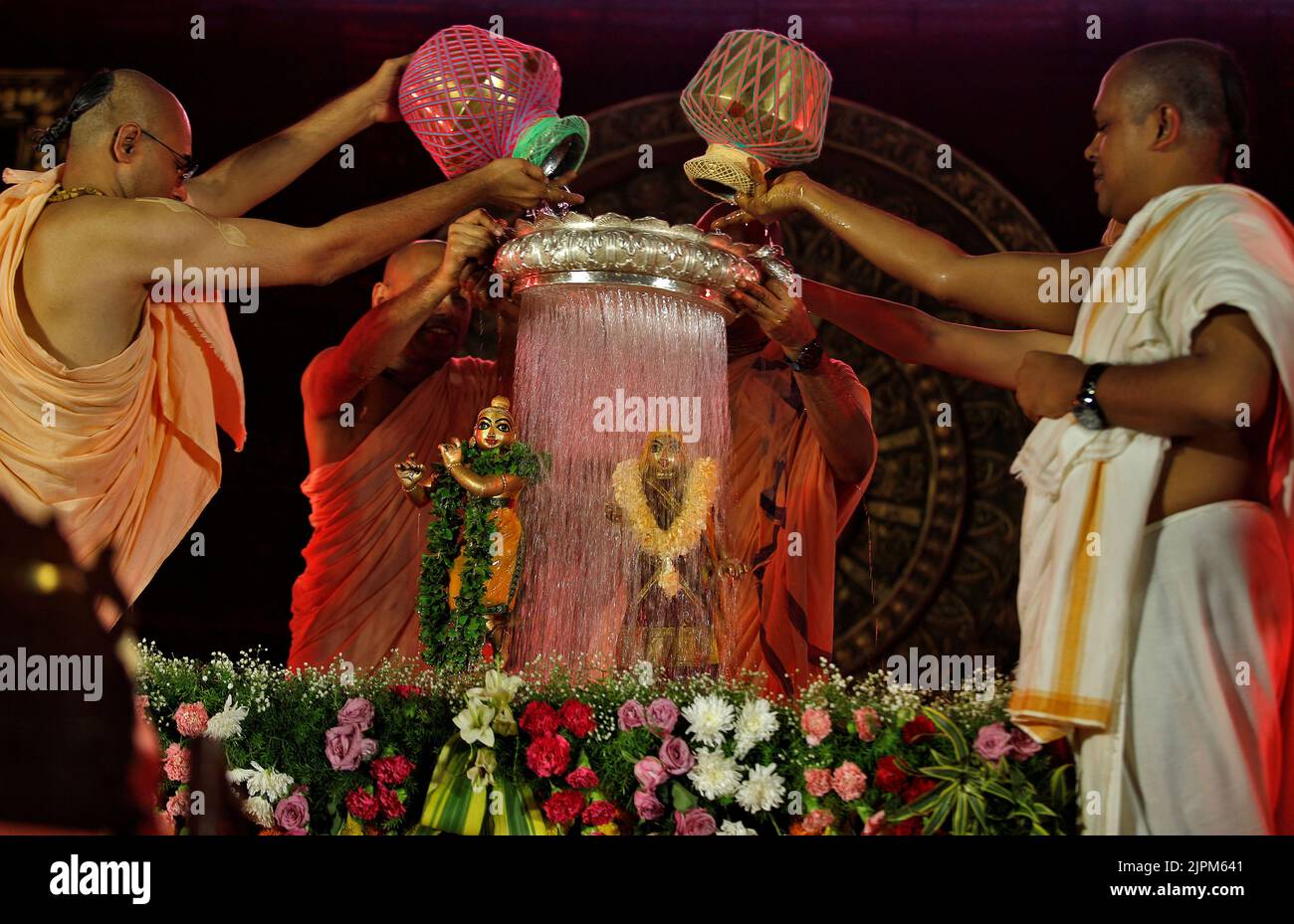 Hindu priests pour holy water over the idols of Hindu Lord Krishna and goddess Radha during the festival of Janmashtami, marking the birth anniversary of Lord Krishna, at a temple in Ahmedabad, India, August 19, 2022. REUTERS/Amit Dave Stock Photo
