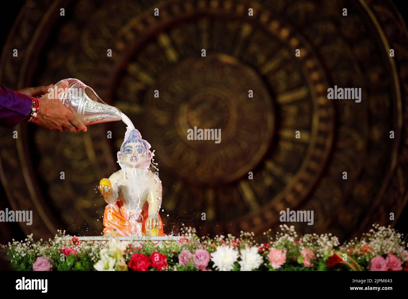 A Hindu devotee pours milk over the idol of Hindu Lord Krishna during the festival of Janmashtami, marking the birth anniversary of Lord Krishna, at a temple in Ahmedabad, India,, August 19, 2022. REUTERS/Amit Dave     TPX IMAGES OF THE DAY Stock Photo