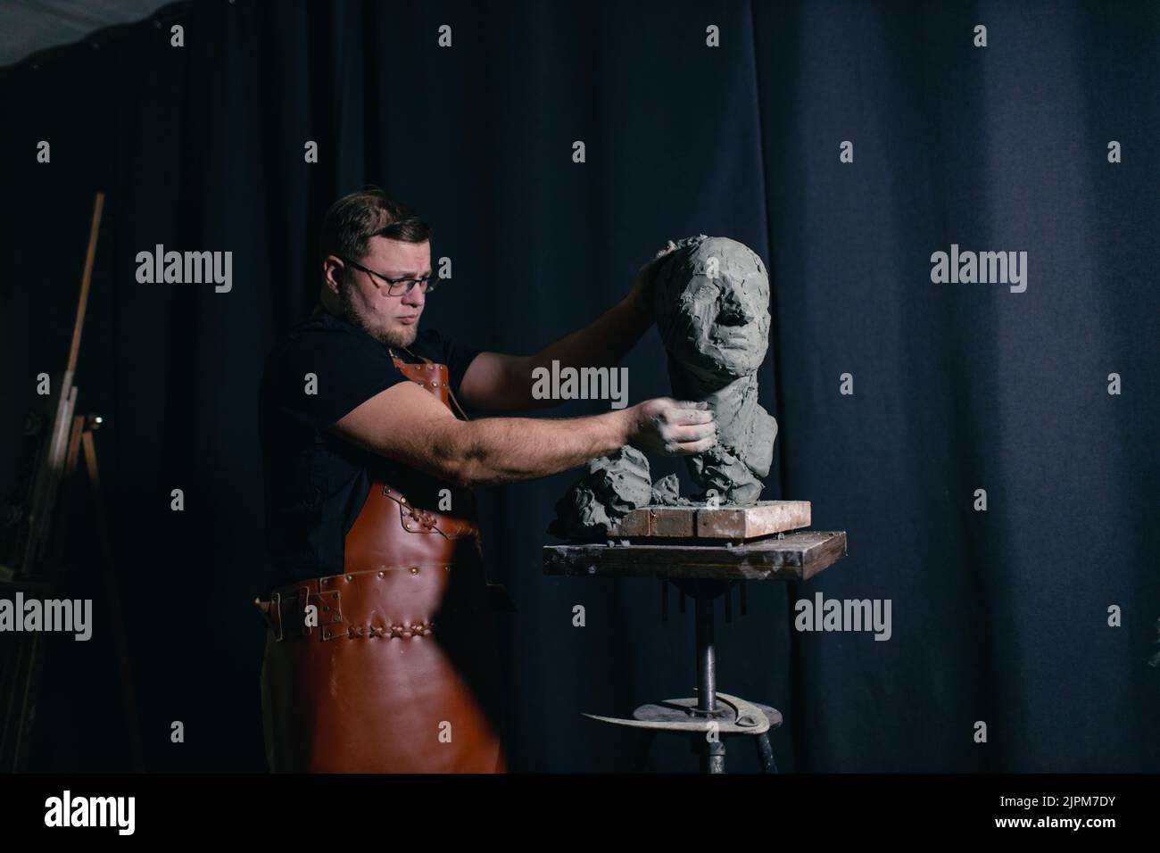 Man sculptor creates sculpt bust clay human woman sculpture. Statue