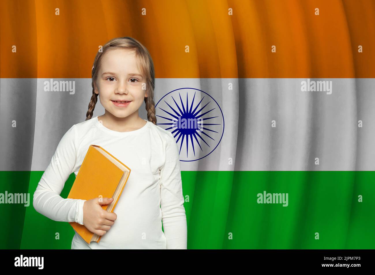 Beautiful small kid girl with book on flag of India background. Learn Hindi language concept. Stock Photo