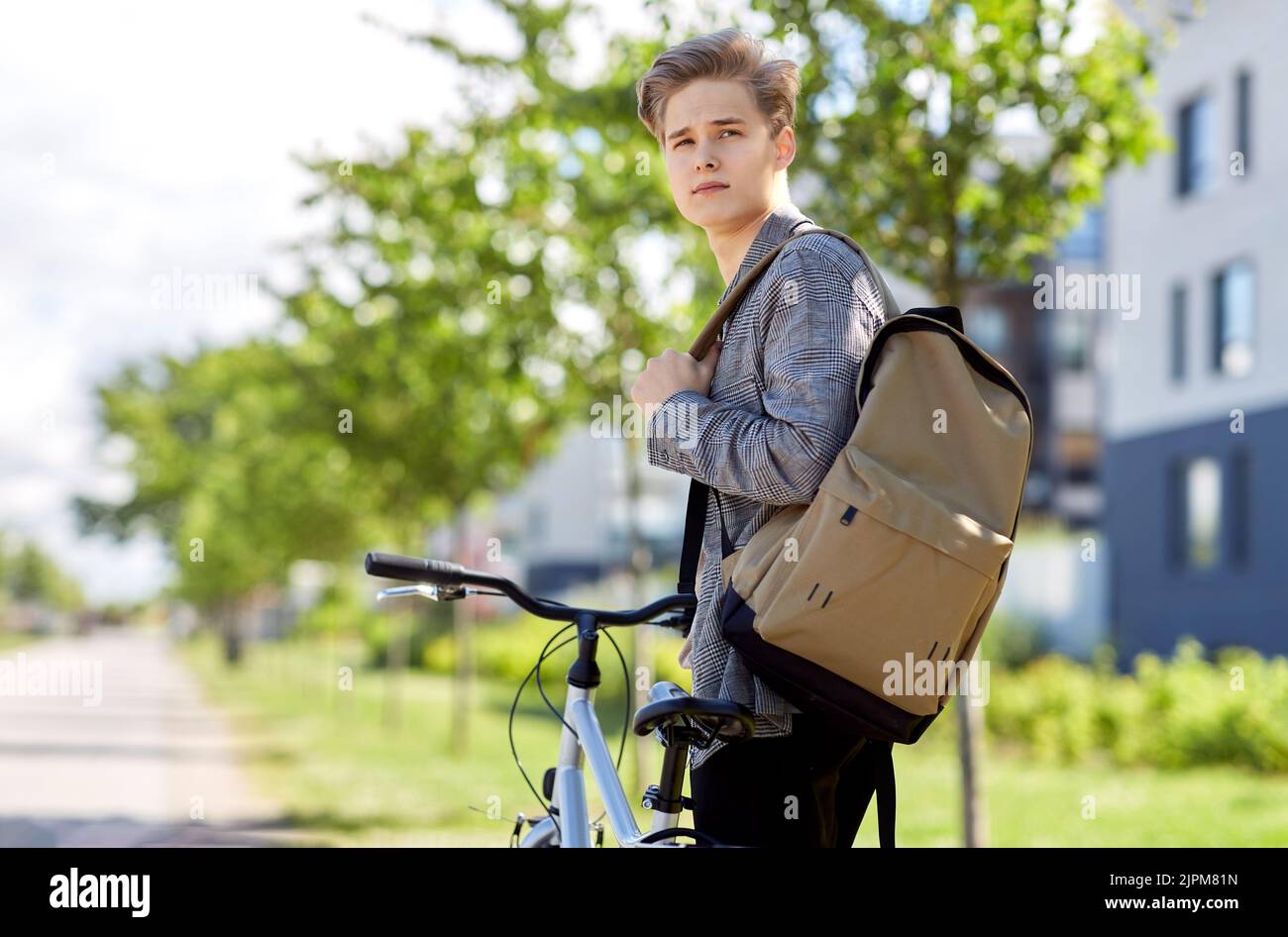 young man with bicycle and backpack on city street Stock Photo