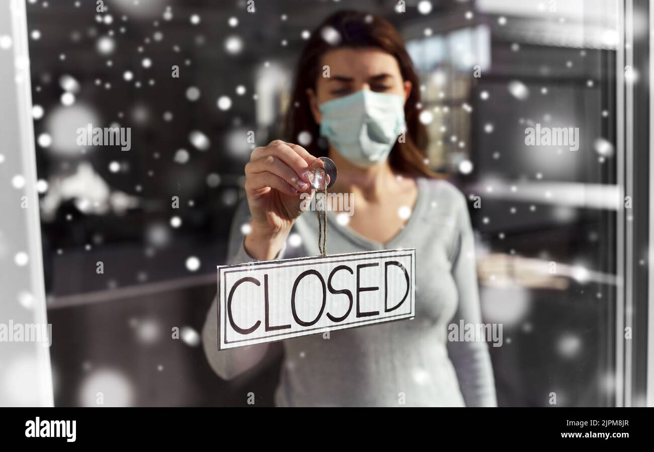 woman in mask hanging banner closed on door Stock Photo