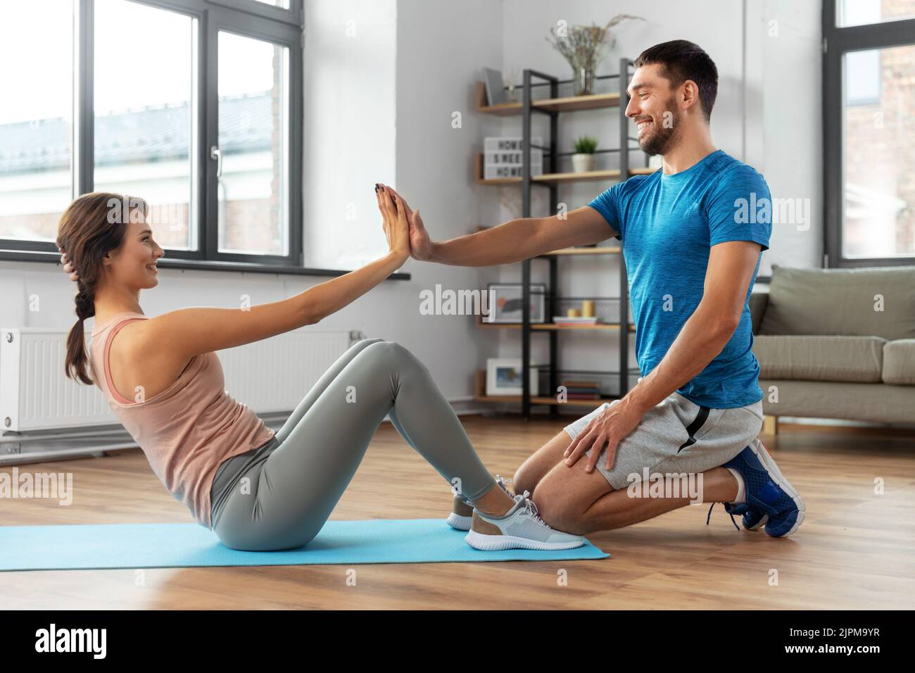 woman with personal trainer doing sit ups at home Stock Photo