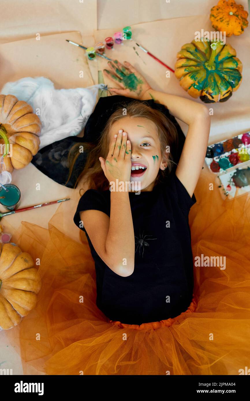 Top view of Smiling girl lying on the floor between drew pumpkin ...