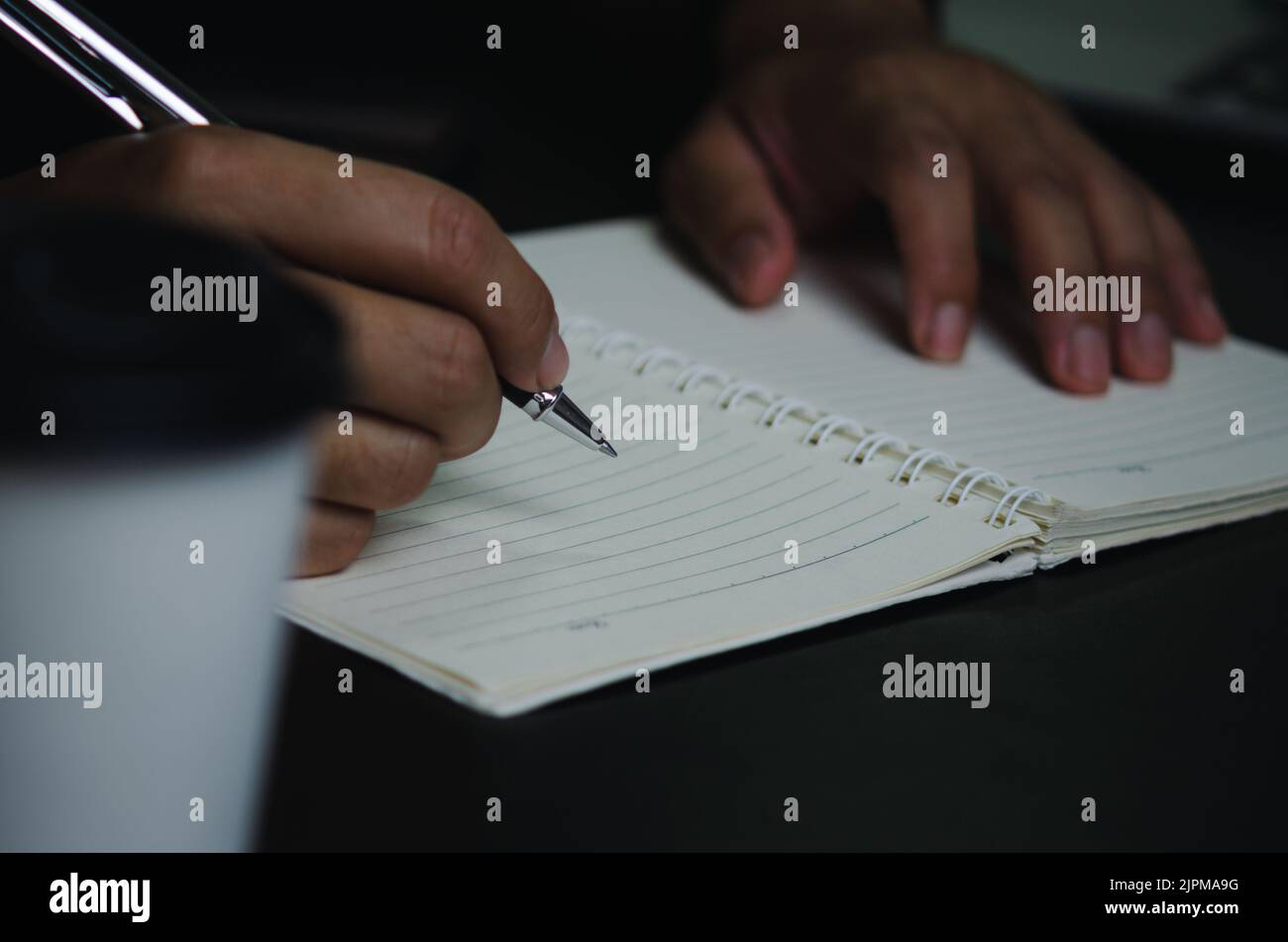 Man hand holding pen write note diary on book Stock Photo - Alamy