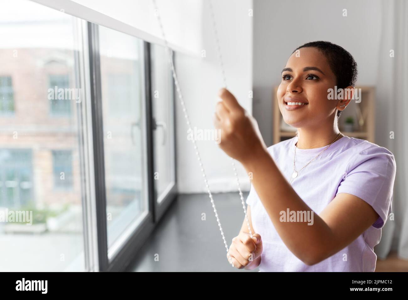 woman opening window roller blinds Stock Photo