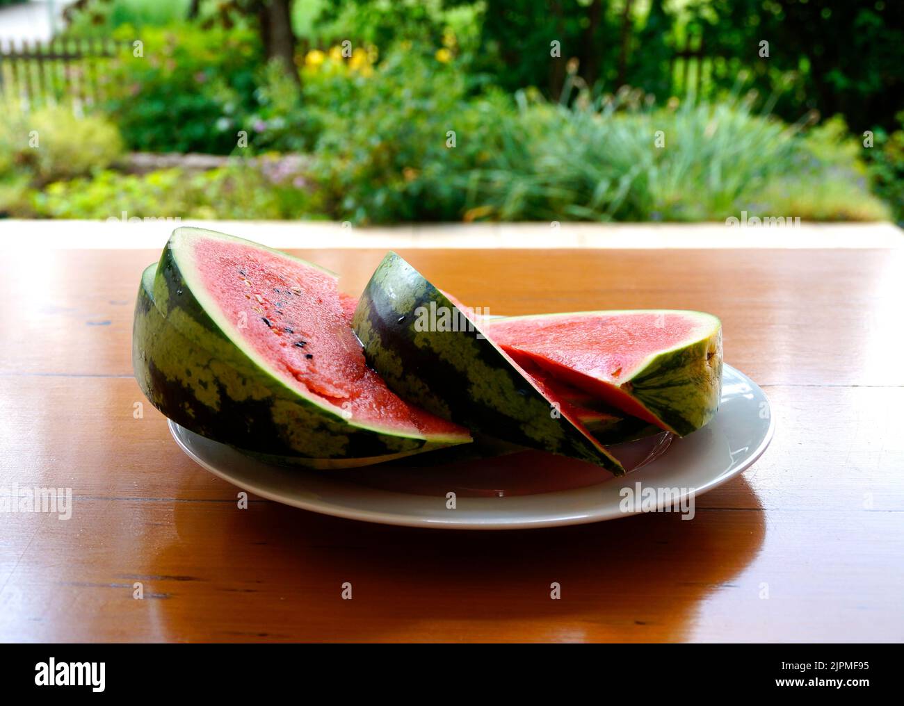 juicy bright red slices of watermelon on the plate on the table in the garden Stock Photo