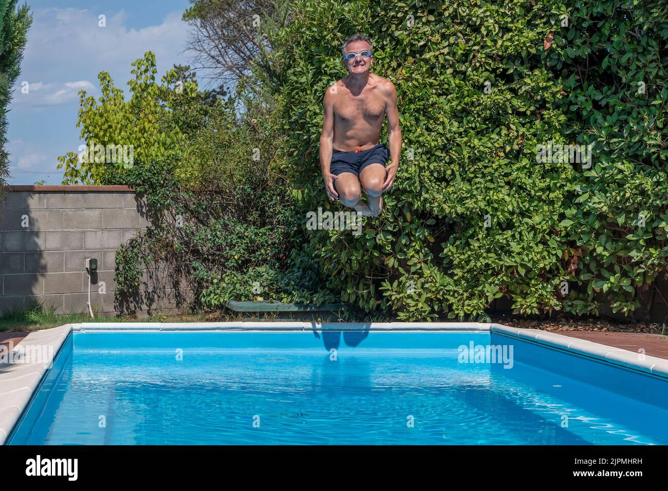Middleaged white man with funny goggles dives into the pool
