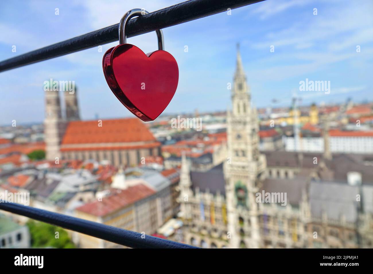 A heart-shaped lock, and in the background panoramic view of the old medieval Gothic architecture City Hall building at Marienplatz. Square.  Munich, Stock Photo