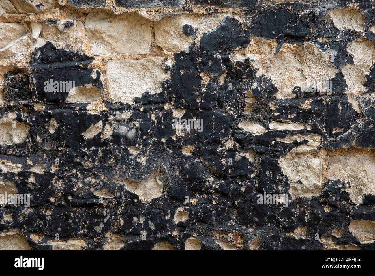 Ancient wall area with blackened lime plaster rendering flaking off Stock Photo