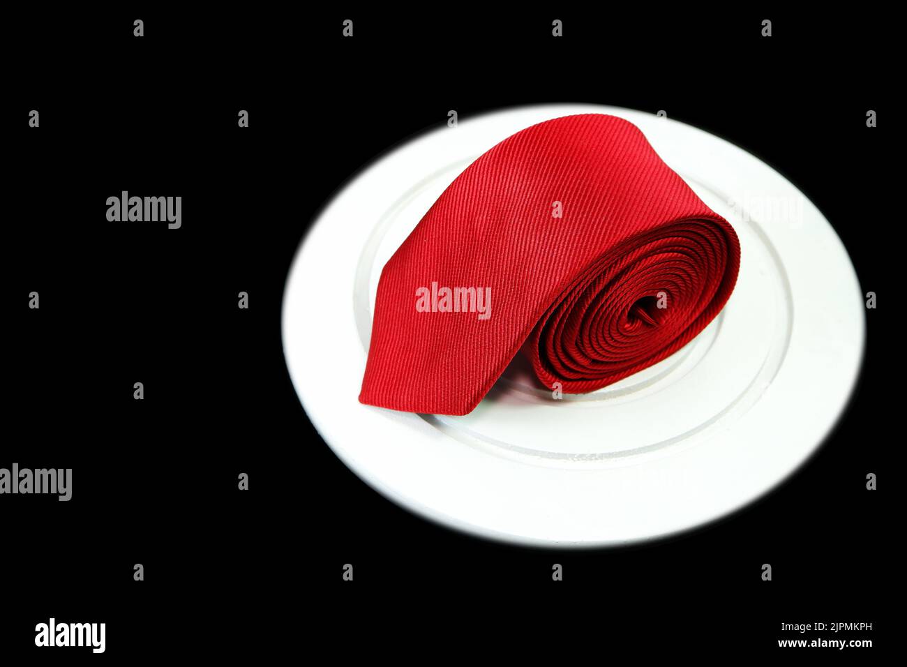 red color polyester fabric necktie rolled isolated on white color display mate with black background Stock Photo