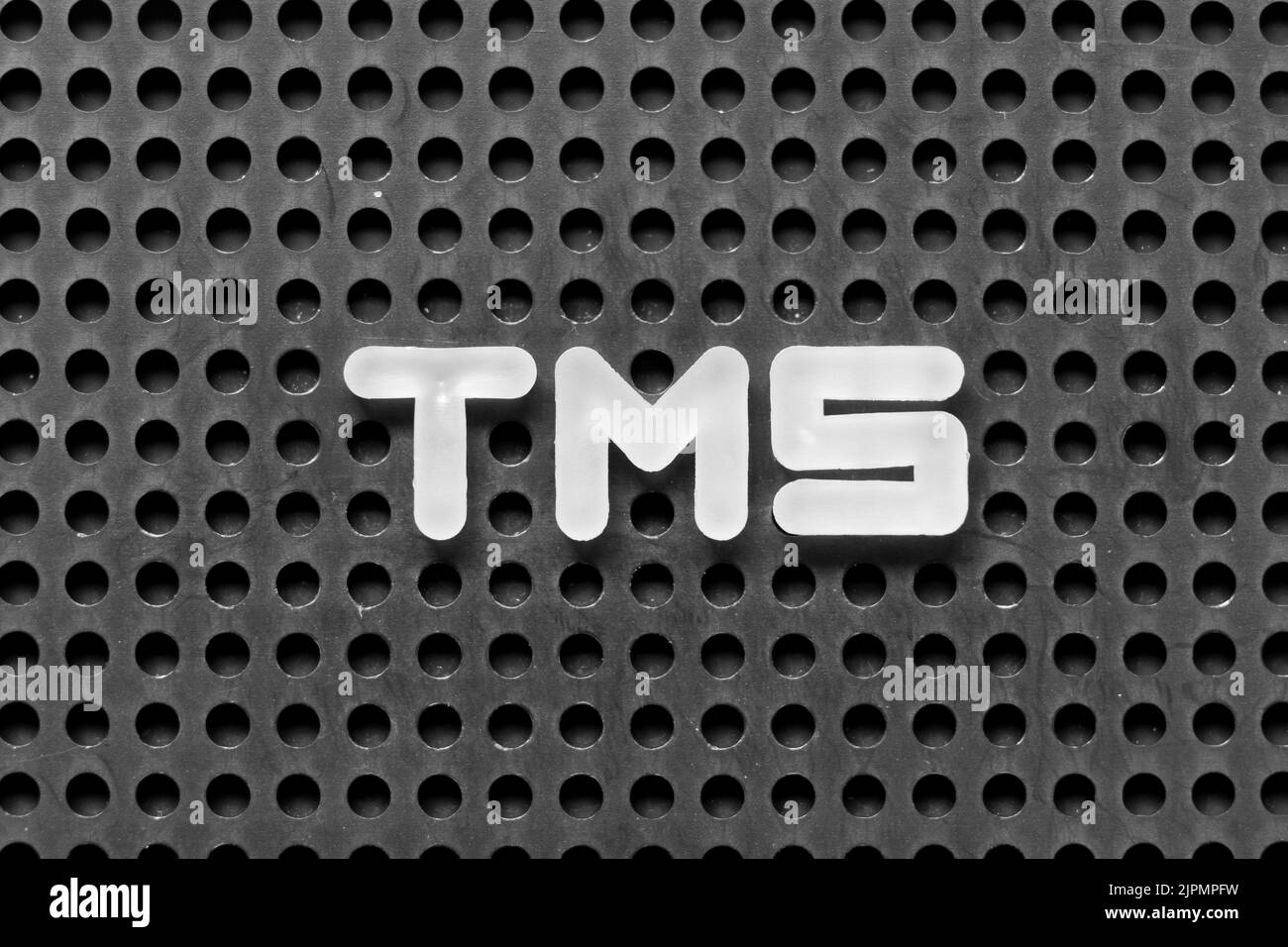 White alphabet letter in word TMS (Abbreviation of Transportation management system or Transcranial magnetic stimulation) on black pegboard background Stock Photo