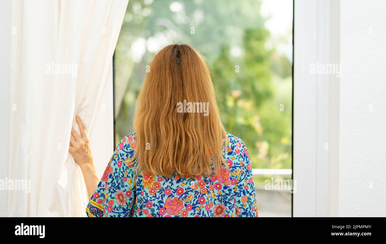 Young woman looks through the window, Stock Photo