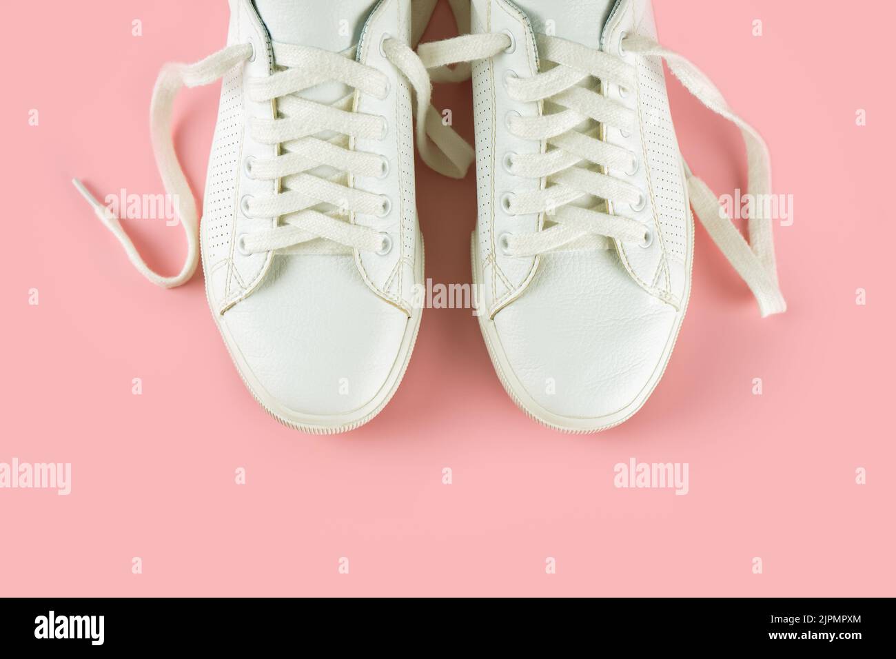 Pair of white sneakers on pink background. Unisex shoes, stylish white