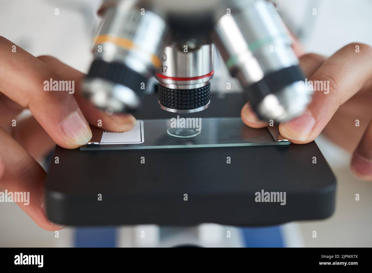Extreme close-up of unrecognizable teenager examining sample with help of modern microscope while wrapped up in finishing school project Stock Photo
