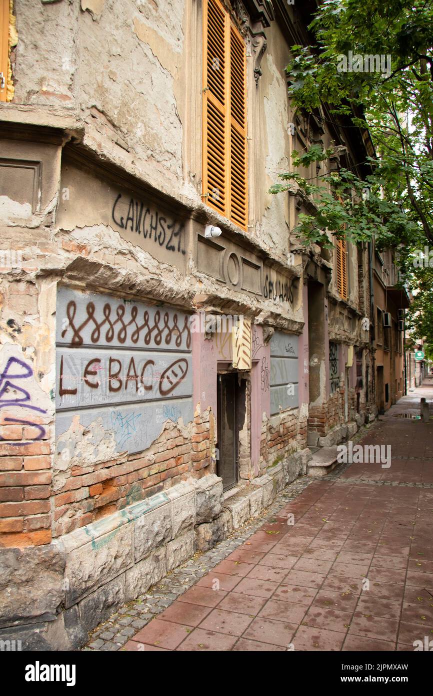 Belgrade-Serbia - June 15, 2022: Old ruined house with graffiti 'Bread' and a drawing of it on a facade wall in quite empty street in Dorcol Stock Photo