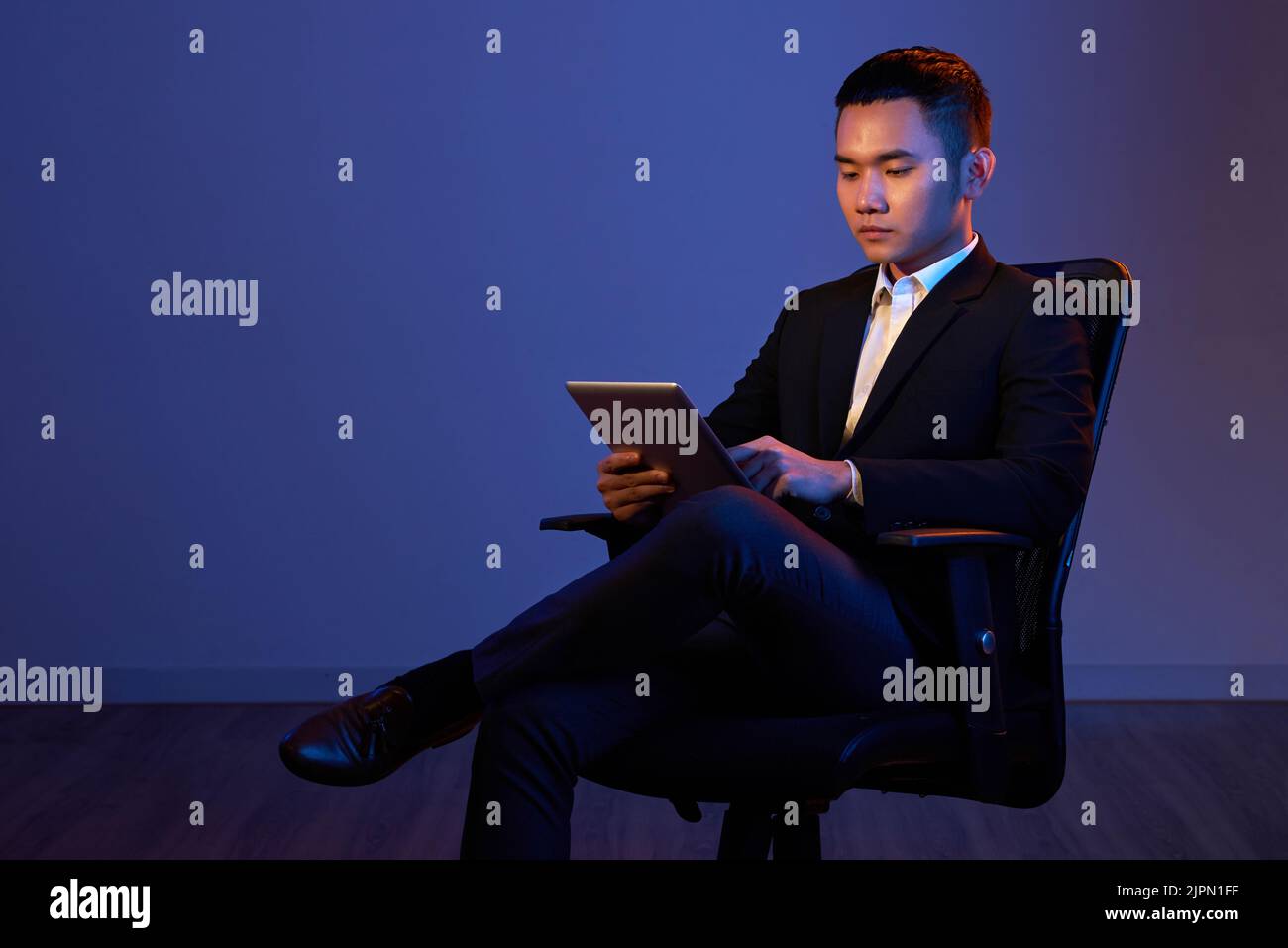 Young confident entrepreneur reading information on tablet computer Stock Photo