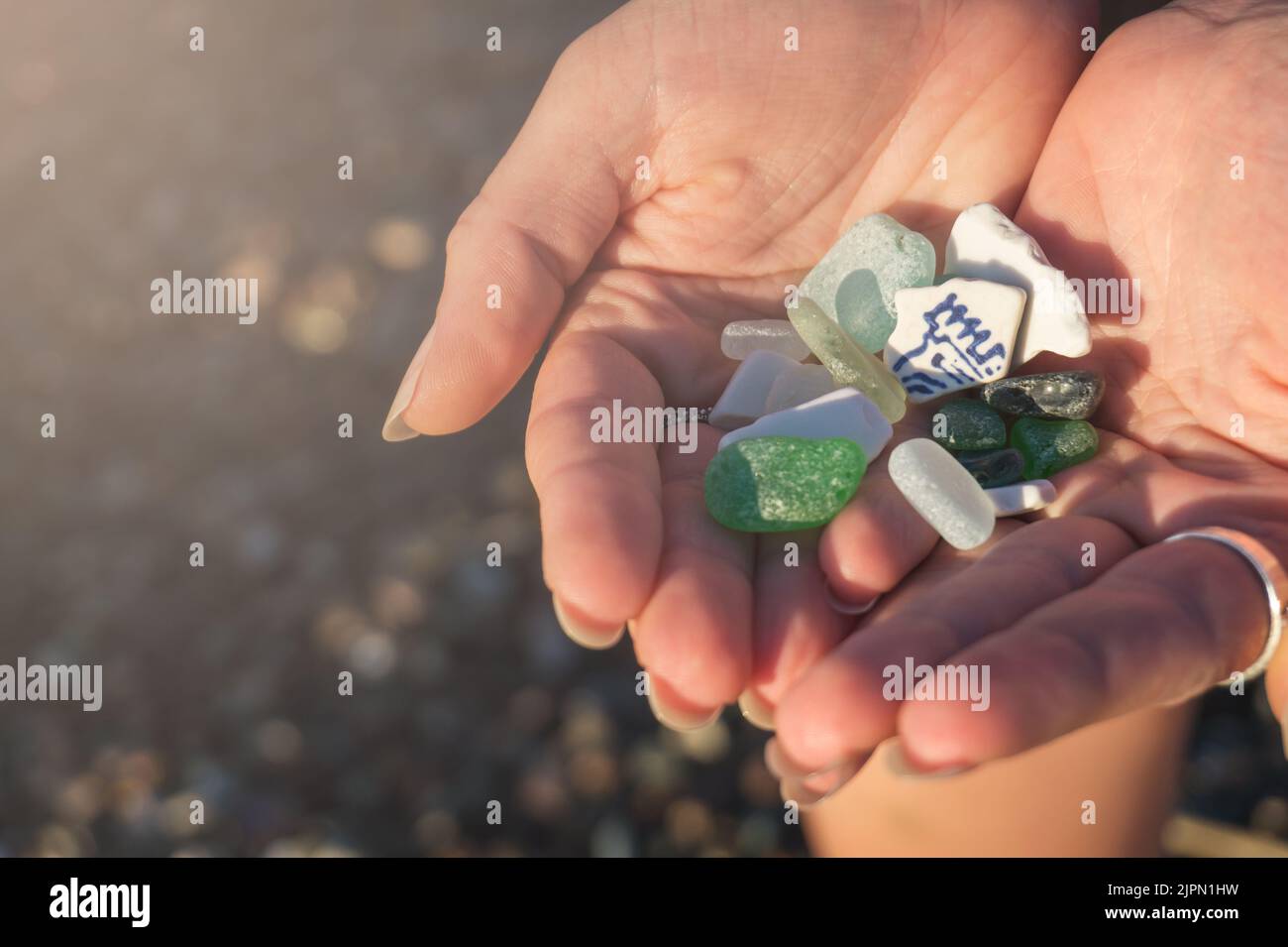 Sea glass and sea pottery pieces in the hands of a young woman close-up Stock Photo