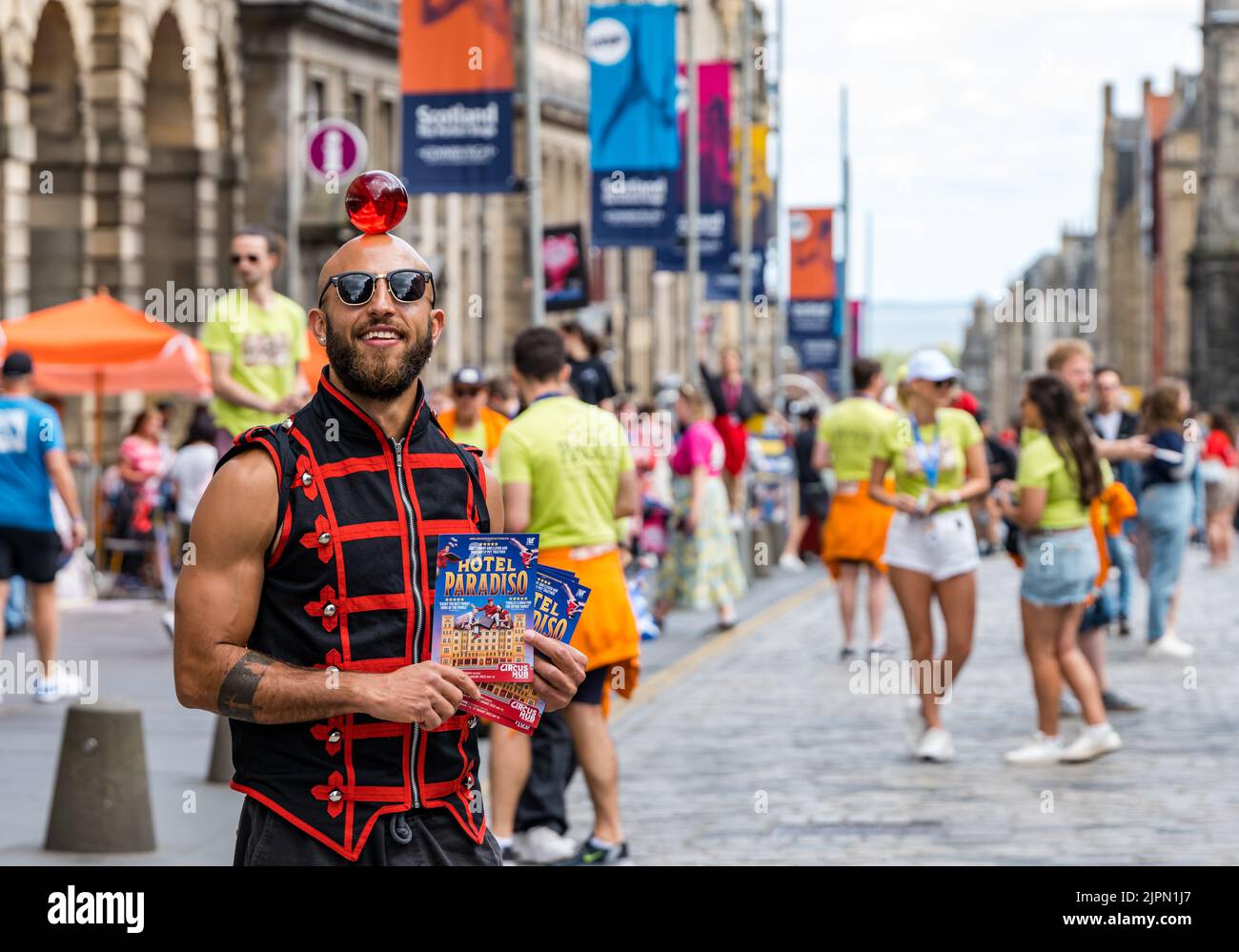 Edinburgh, Scotland, UK, 19th August 2022. Fringe performers on the Royal Mile: the street is packed with Fringe-goers, street performers and cast of shows handing out leaflets on a sunny day. Pictured: a circus performer from Lost in Translation Hotel Paradiso circus show. Credit: Sally Anderson/Alamy Live News Stock Photo