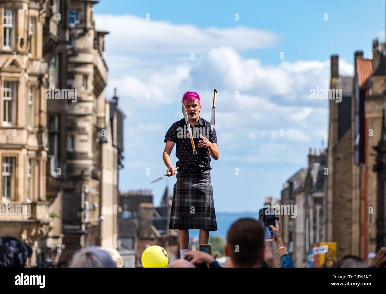 Edinburgh, Scotland, UK, 19th August 2022. Fringe performers on the Royal Mile: the street is packed with Fringe-goers, street performers on a sunny day. Pictured: a sword juggler. entertains the crowd Credit: Sally Anderson/Alamy Live News Stock Photo
