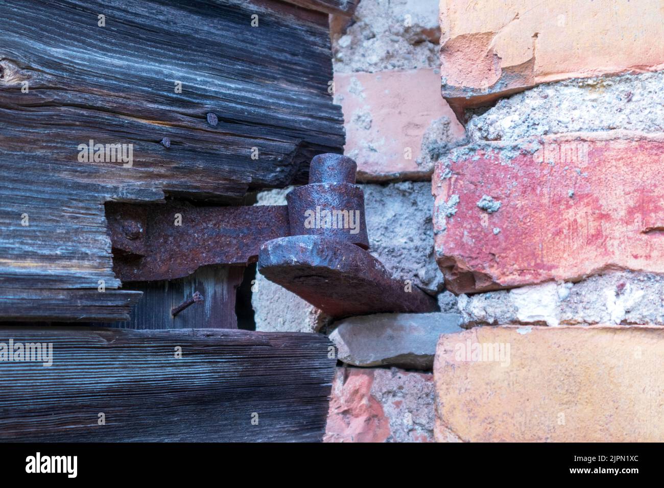 An old rusty hinge between an old brick wall Stock Photo