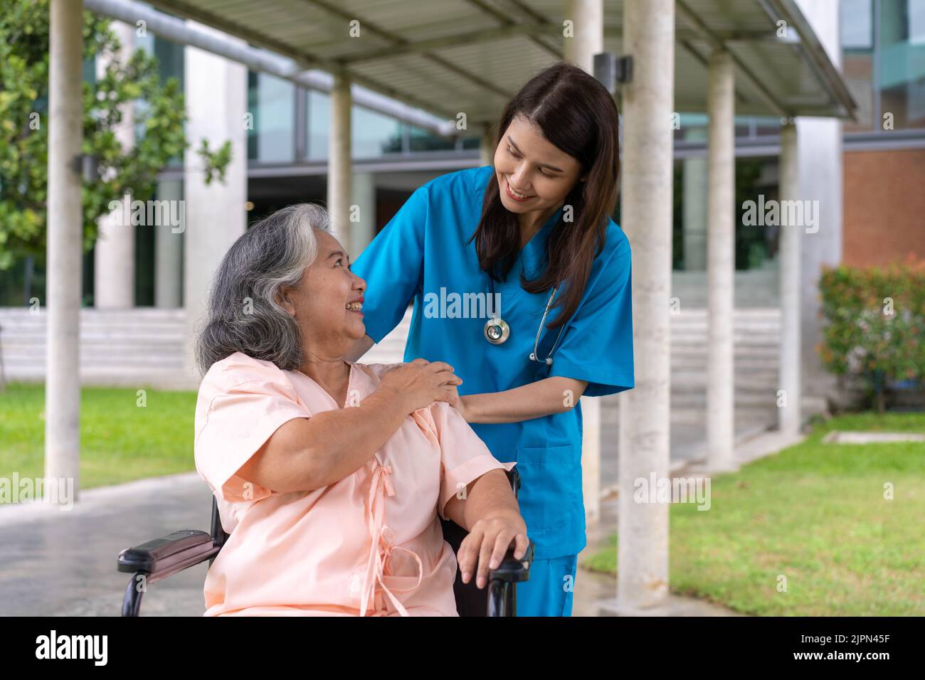 Asian careful caregiver or nurse taking care of the patient in a wheelchair.  Concept of happy retirement with care from a caregiver and Savings and s Stock Photo