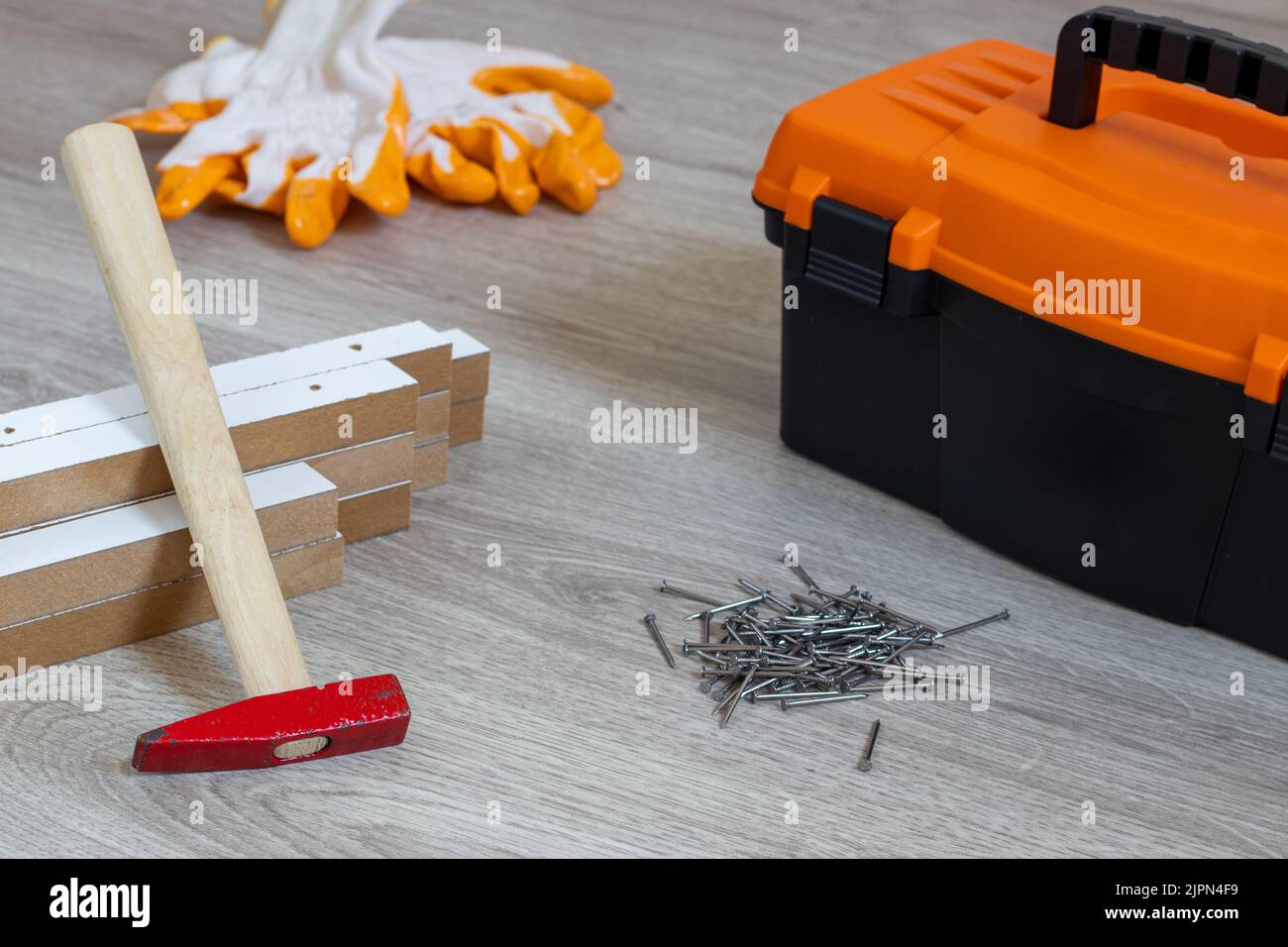 Toolbox on wooden floor . Chipboards, hammer and nails. Stock Photo