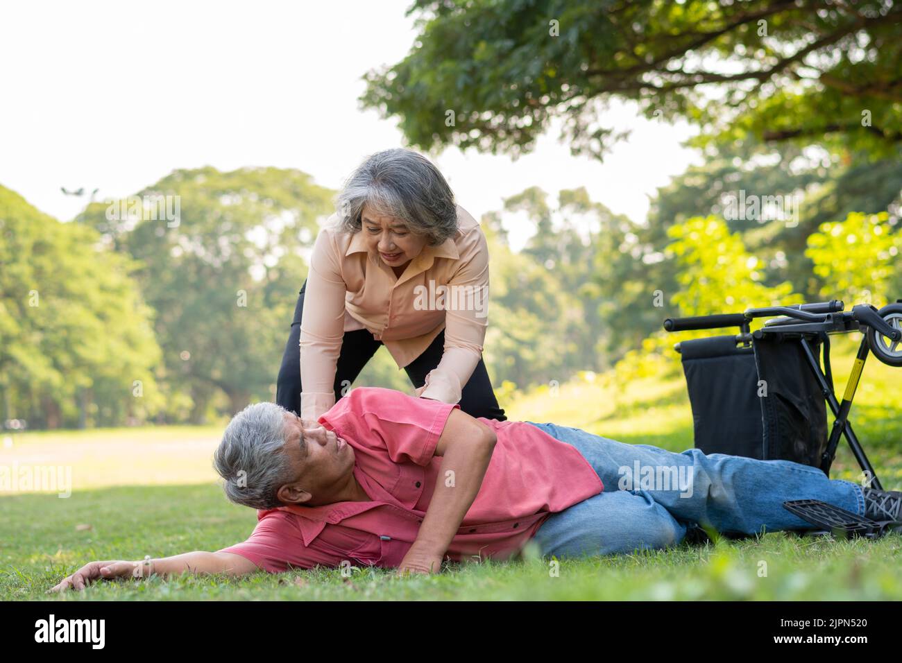 Asian senior man falling down from wheelchair on lying floor after trying push the wheelchair forward and Crying in pain and asking someone for help. Stock Photo