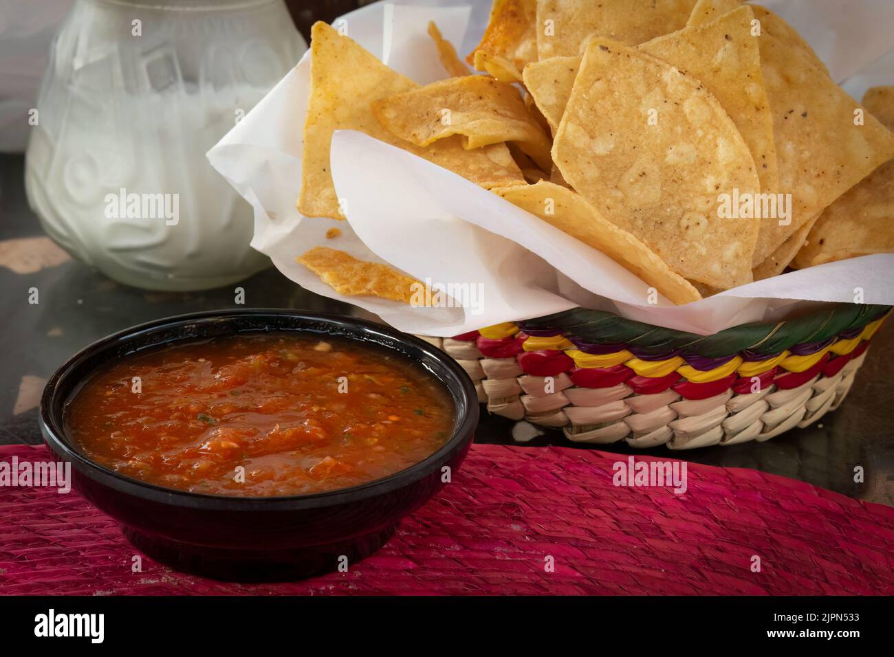 A delicious Mexican appetizer, a large basket of chips and a bowl of salsa sits on a table in San Diego. Stock Photo