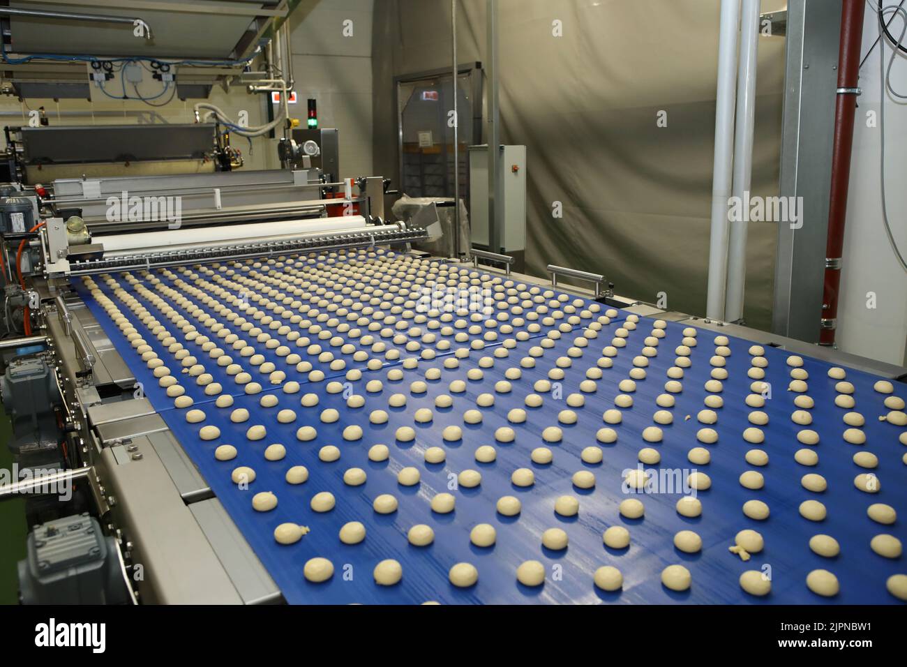 Close up of automated biscuit cookies shape forming machine. Selective focus. machine for making cookies in the factory. Conveyor belt with Cookie dou Stock Photo