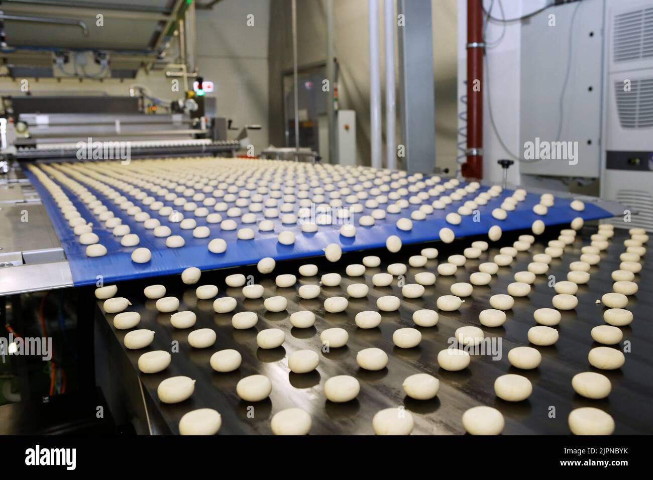 Close up of automated biscuit cookies shape forming machine. Selective focus. machine for making cookies in the factory. Conveyor belt with Cookie dou Stock Photo
