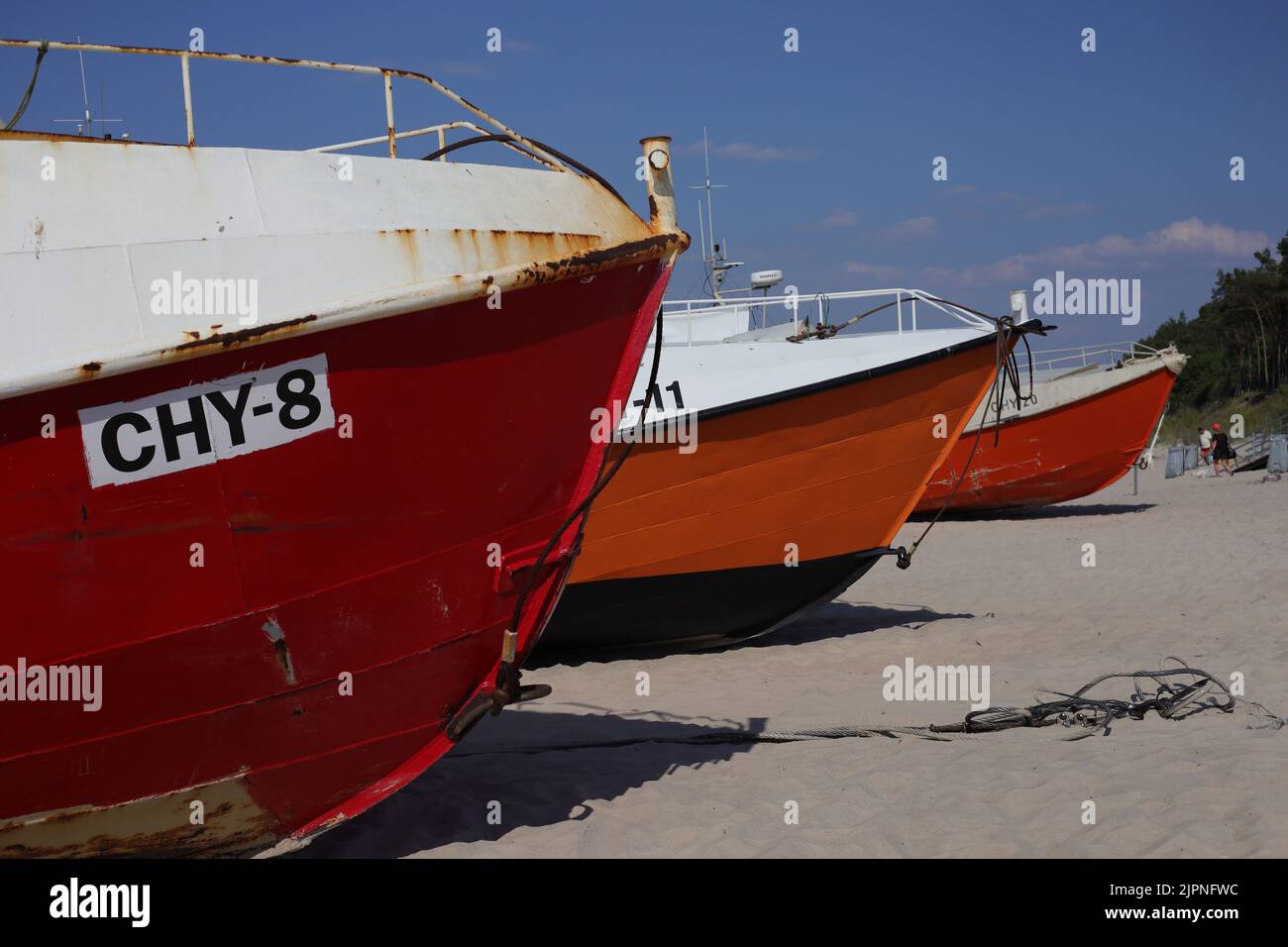 A closeup of red and orange fishing boats on the beach in Chlopy, Poland Stock Photo