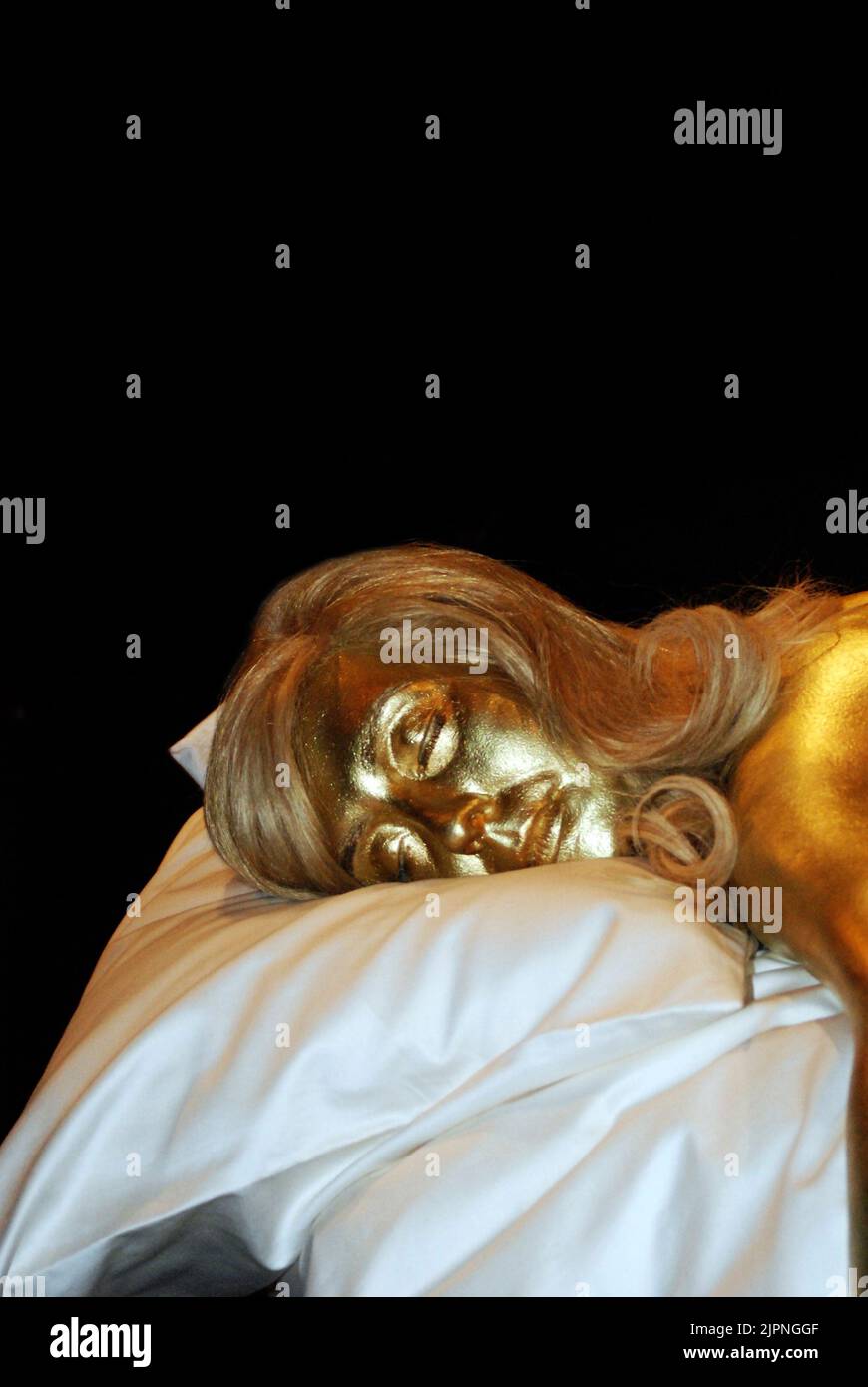 From Designing 007: 50 years of James Bond Style, showing a model of actress Shirley Eaton, lying dead on a bed, from the iconic scene in Goldfinger. Stock Photo