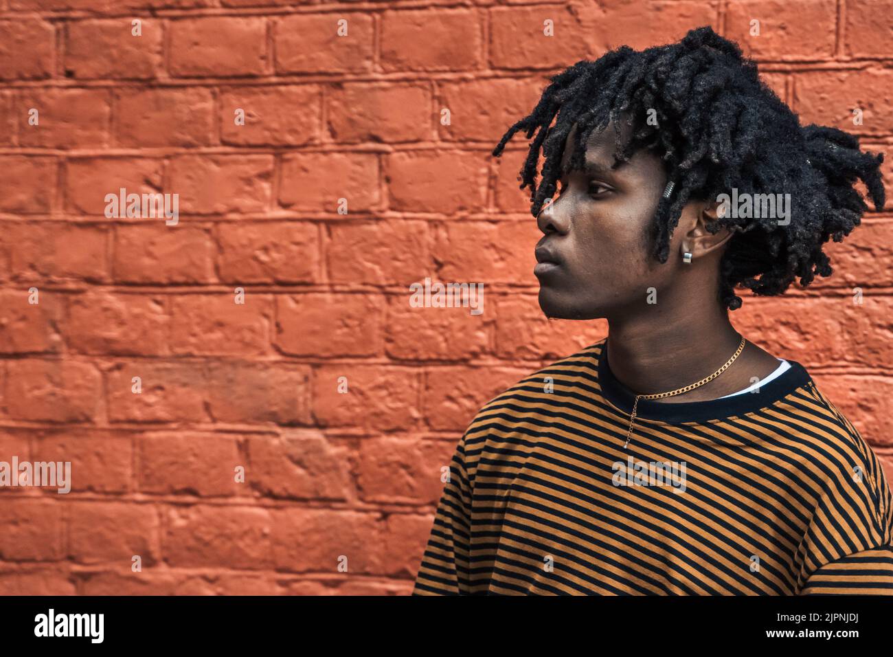 Young handsome stylish black man with natural hair dreadlocks. Afroamerican guy.Stairs,wall painted with graffiti in poor quarter of street art cultur Stock Photo