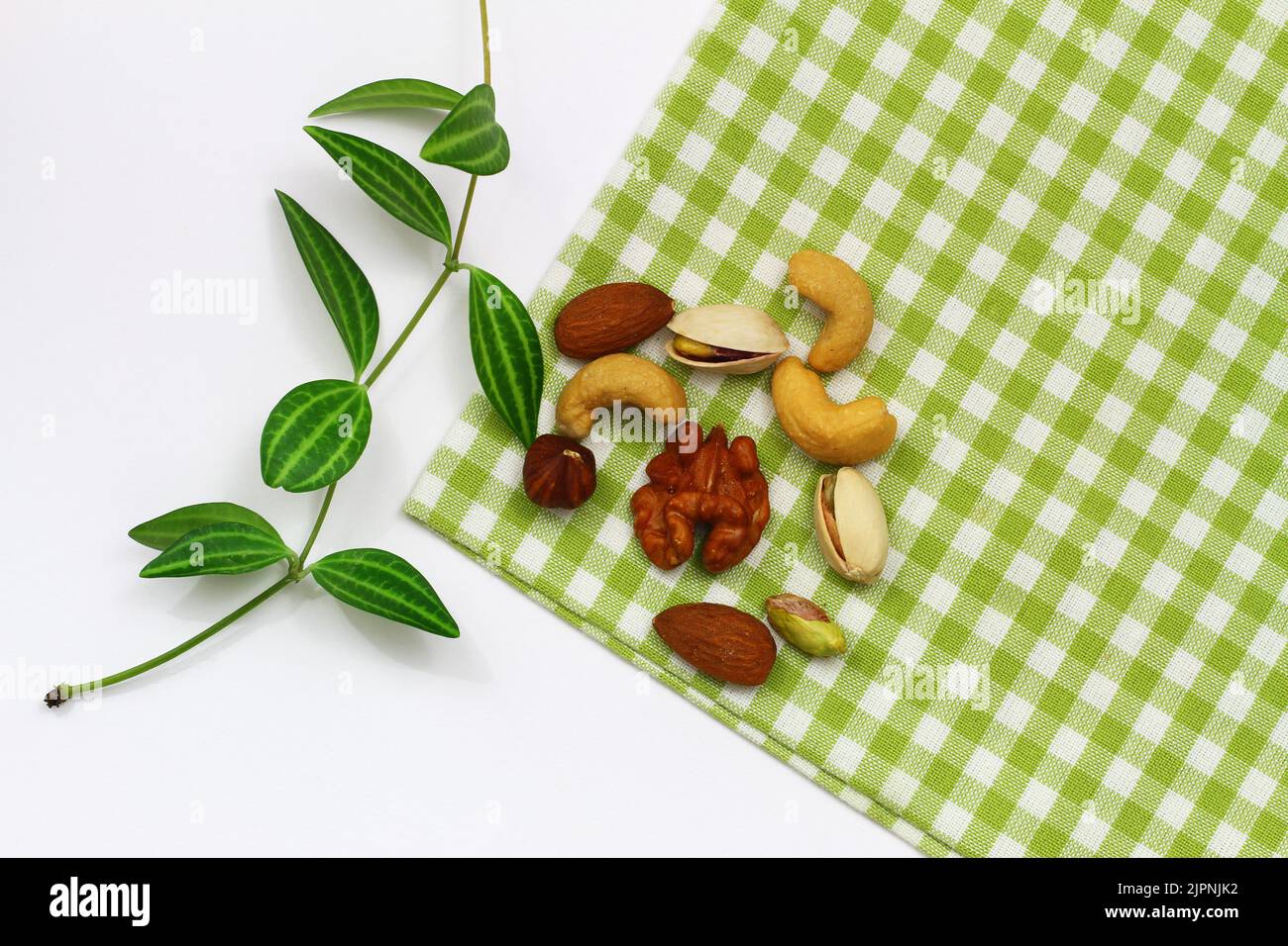 Pistachio nuts, walnuts, cashew nuts, hazelnuts, peanuts, almonds on green and white checkered cloth Stock Photo