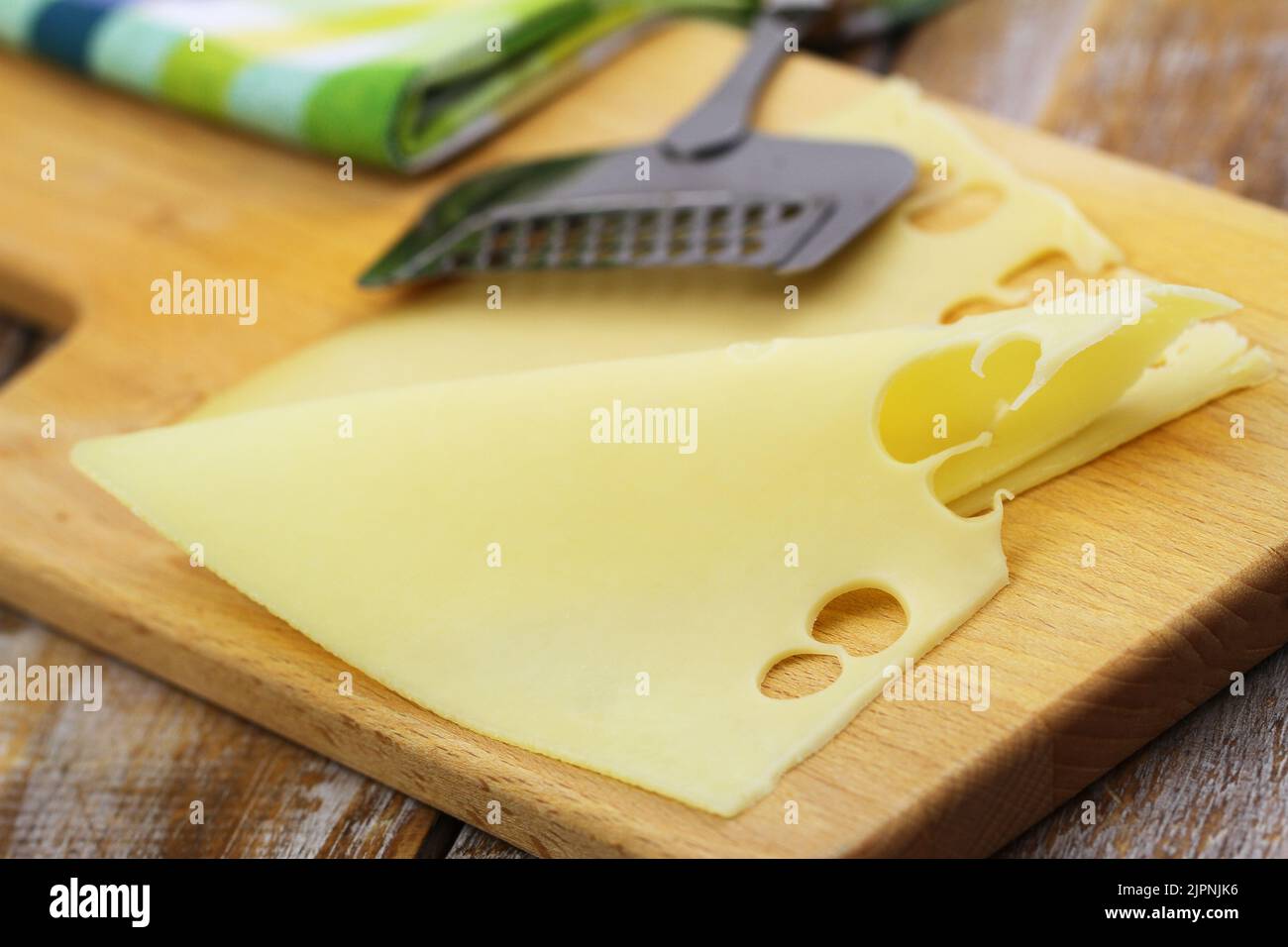 Slice of tasty Swiss cheese on wooden board, closeup Stock Photo